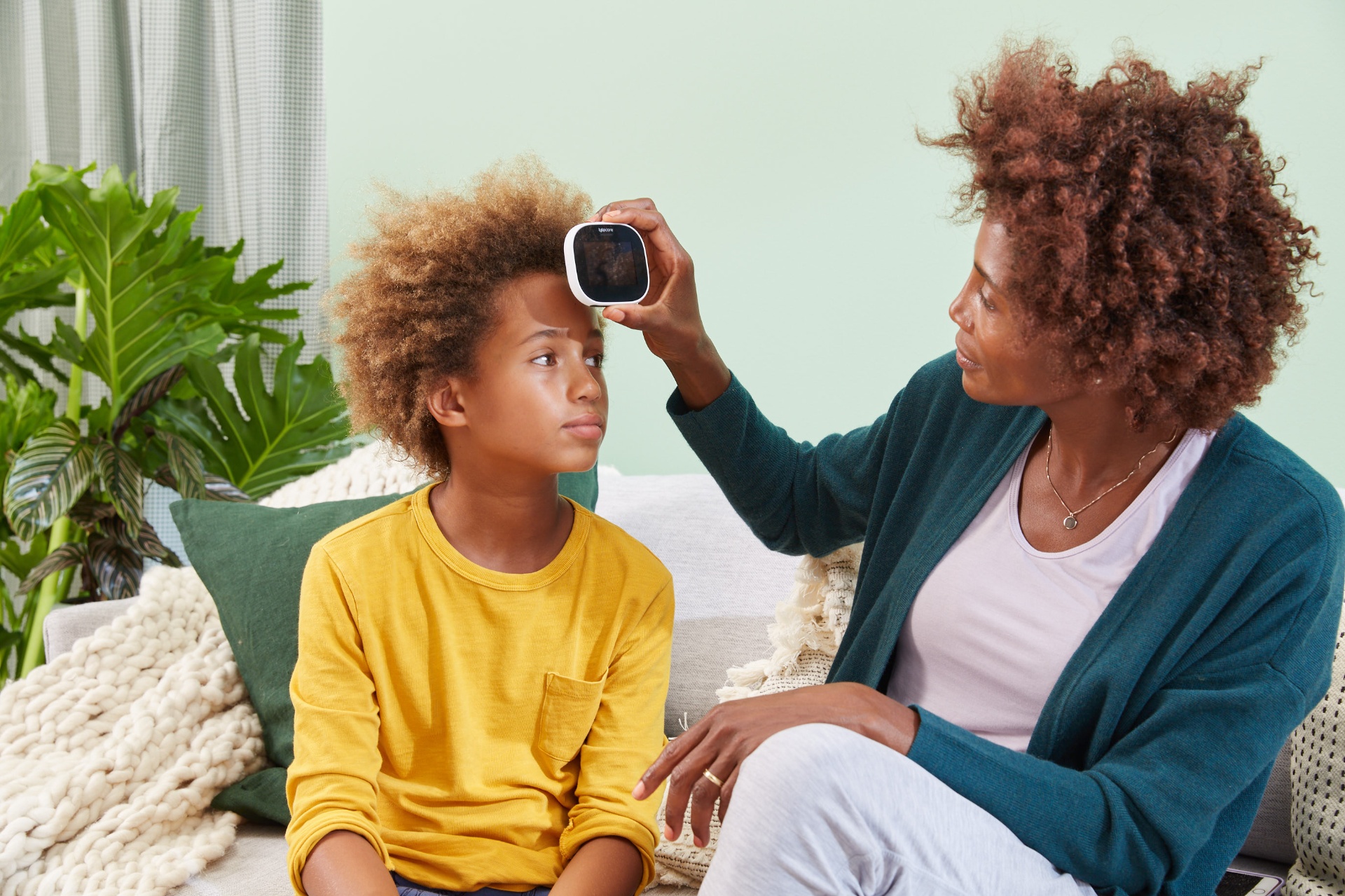 Mãe medindo temperatura do filho com TYTO CARE