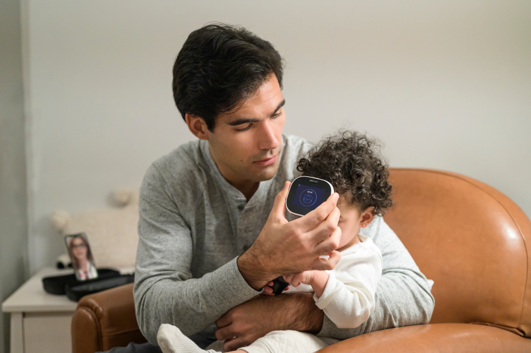 Pai examinando bebê com TYTO CARE